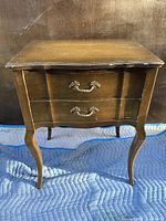 Front view of wooden silverware cabinet showing two drawers with metal ornate handles.