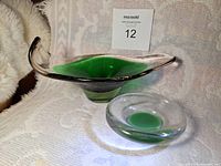 Two art glass bowls on white textured fabric, one large with green center and clear edges, one smaller round with green center and clear ring.