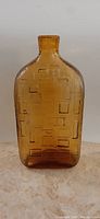 Front view of amber Brutalist style Empoli bottle with geometric rectangle patterns on front surface.