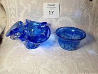 Two blue glass bowls shown side by side on a fabric surface with a numbered tag behind them.