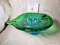 Three-quarter side view of a green and blue glass bowl with organic flowing shape and smooth glazing