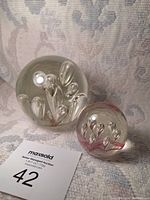 Both glass paperweights together showing bubble detail and size difference