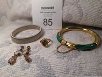 Five-piece costume jewellery set shown on fabric background: two bangles, one ring, and two pairs of clip-on earrings.