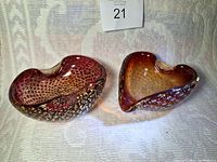 Two small hand blown glass bowls side by side on a cloth background, showing kidney and heart shapes with gold flecks and bubbles.