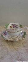 Photo of Royal Albert teacup and saucer side view showing floral pattern, gold trim, and green decorative accents.