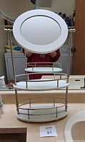 Full view of the vanity mirror with two oval shelves placed on bathroom countertop.