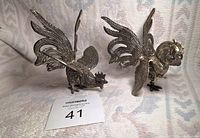 Full view of two silver-toned fighting cockerel figurines showing detailed feathers and raised wings in a fighting stance.