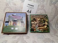 Two decorative match containers displayed side by side on a light-colored textured surface with a MaxSold auction number 44 card in the background.