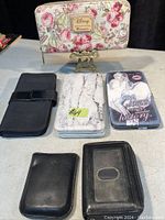 Photo of 5 wallets including a Disney floral wallet, black leather wallet, marble design wallet, printed fashion wallet, and plain black wallet.