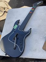 Full view of black Kramer Guitar Hero controller showing body, strum bar, whammy bar, and neck with colored fret buttons.
