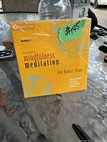 Photo of sealed yellow/orange box set of guided mindfulness meditation audio CDs by Jon Kabat-Zinn.