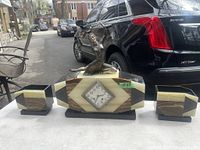 Full front view of central clock and two garniture vases on table outdoors