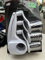 Photo showing the rotary grater set with three different stainless steel drums in original packaging labeled 'Rotary Grater Moulin A Raper'.