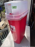 Red plastic Sterilite container with white lid, sits on a table, with price sticker visible