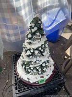 Full view of the lighted village Christmas tree sculpture with snowy evergreen branches and detailed village figures.