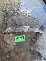 Metal folding knife with wolf design on handle and curved blade.