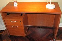 Front view of wood computer desk and filing cabinet with two drawers, one drawer locked, on casters.