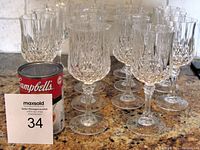 Front view of 14 Crystal Of America wine glasses arranged in rows on a granite countertop with a Campbell's soup can for scale.