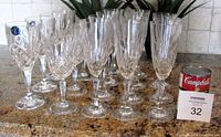 Full view of 18-piece set of crystal glassware including red wine glasses, white wine glasses, and champagne flutes arranged in rows on a countertop.