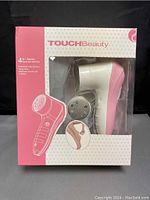 Front view of the boxed Touch Beauty 4 in 1 electric dead skin remover device showing the main unit through the clear packaging window.