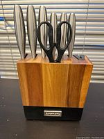 Front view of the acacia wood knife block with 6 knives and all-purpose shears inserted, showing handles and scissors.