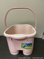 Side view of rectangular pink plastic foot soak bucket with handle showing bucket shape and sticker on side.
