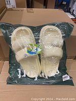Slippers sealed in original packaging, showing the light yellow color and overall design.