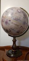 Full view of antique globe showing detailed ocean map and decorative elements