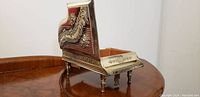 Side view of silver grand piano music box showing musical note engravings and floral designs