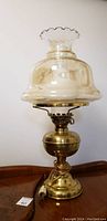 Full view of the antique brass lamp assembled with the clear etched floral glass shade in place.