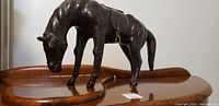 Front side view of the large antique leather horse statue showing detailed muscles and leather saddle.
