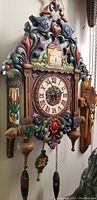 Frontal view of carved wooden cuckoo clock with multicolor paint and Roman numeral face
