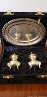 Open original black box with two silver shakers and oval silver tray inside, showing overall presentation and condition.