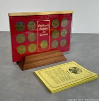View of red background display case with 12 gold plated floral emblem coins and booklet.