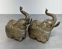 Front view of two silver elephant betel boxes, showing detailed heads with raised trunks and tusks.