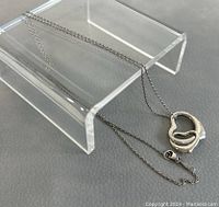 Full view of necklace draped over clear acrylic stand showing chain and heart pendant