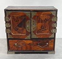 Front view of cabinet with double doors closed showing wood veneer and brass hardware.