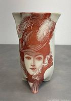 Front view of footed vase showing woman's face with feathered hat artwork