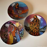 Three decorative plates arranged in a group showing overall artwork and size.