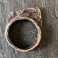 Photo of the hand made rustic sterling silver ring showing band edges and textured uneven rim top, placed on dark stone background.