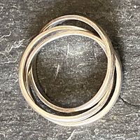 Top view of the sterling silver trinity ring showing three intertwined bands on a dark textured surface.