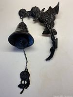 View of full cast iron bell showing bell, mounting bracket with sunflower and foliage design, chain with flower pull.