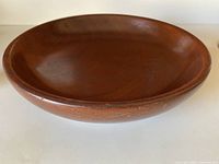 Side angle view showing the shallow depth and gentle curves of the bowl's sides with smooth polished finish.