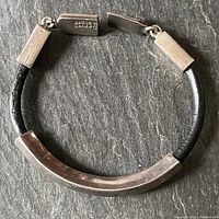 Top view of the vintage men's bracelet showing curved silver tube and leather band with clasp.
