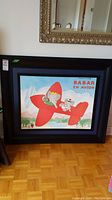 Front view of the framed Babar the Elephant print depicting Babar flying a red airplane with a monkey, titled 'Babar en Avion'.