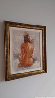 Angled side view of the framed painting showing nude figure from back with detailed golden frame and canvas texture.