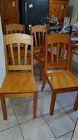 Four handmade wooden chairs with natural finish, arranged in kitchen setting, showing front and sides