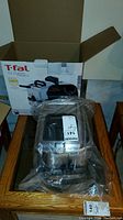 Boxed T-fal EZ Clean Family deep fryer with plastic wrapped unit on a wooden surface.