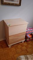 Front view of the nightstand showing two drawers and scalloped feet, light unfinished wood.