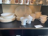 Wide view of various plates, cups, and bowls with gold trim in a cabinet.